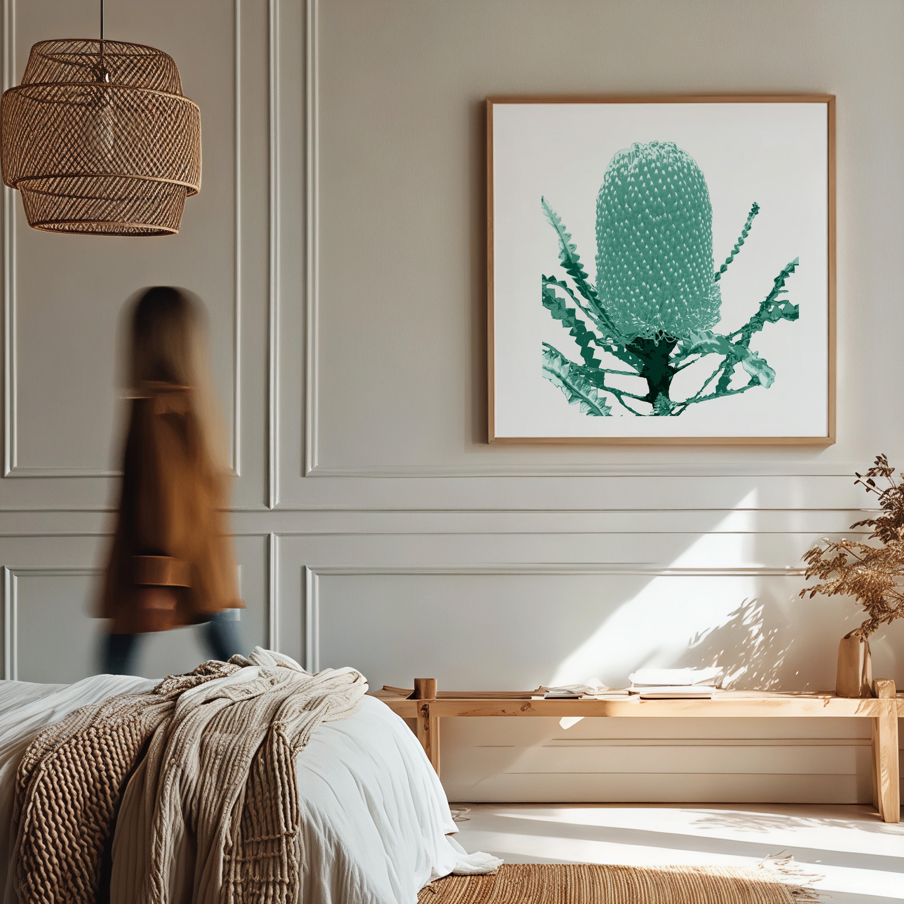 Modern bedroom with a person walking by, framed artwork on the wall, and a vase with plants.