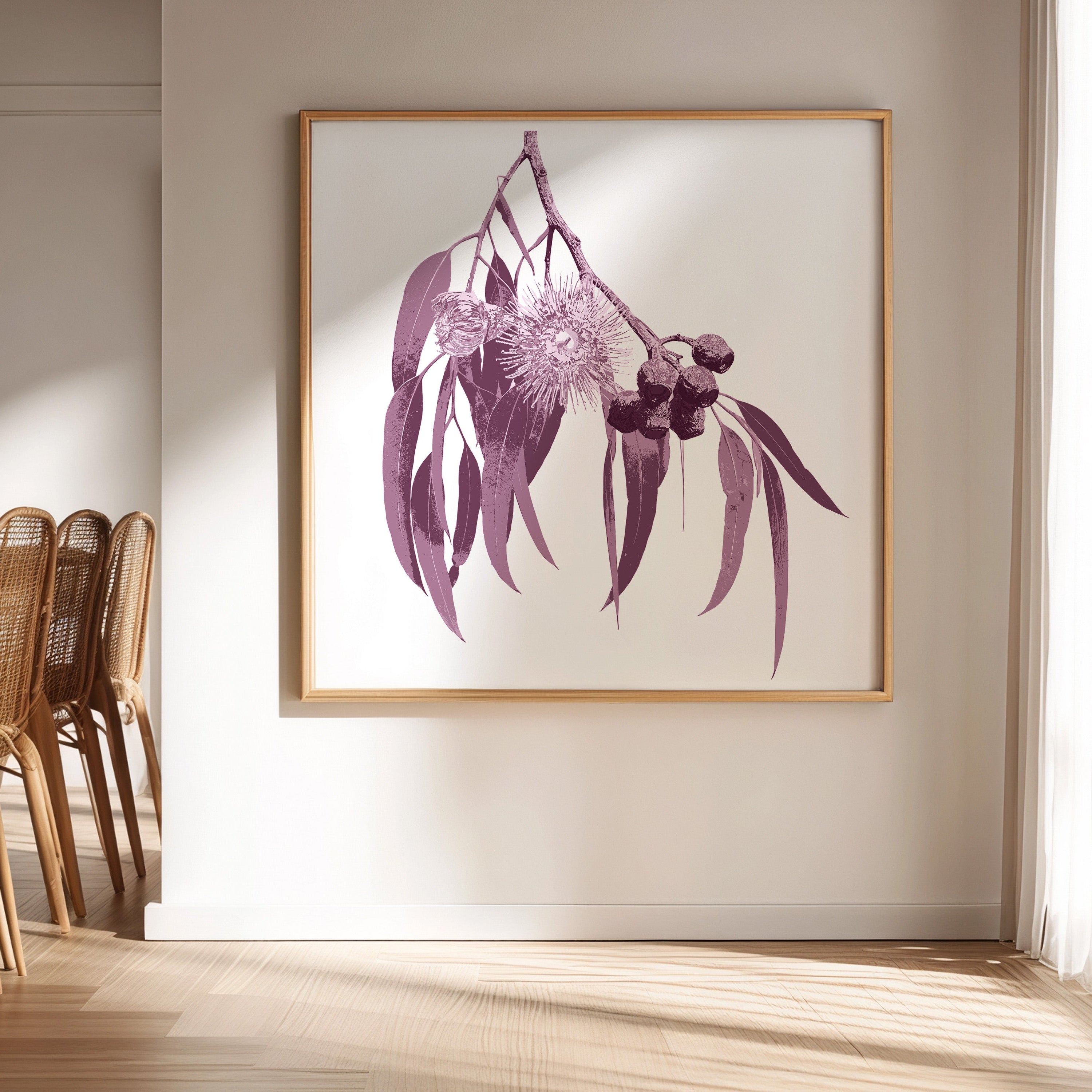 Framed botanical print of eucalyptus leaves and flowers on a wall in a room with wicker chairs.